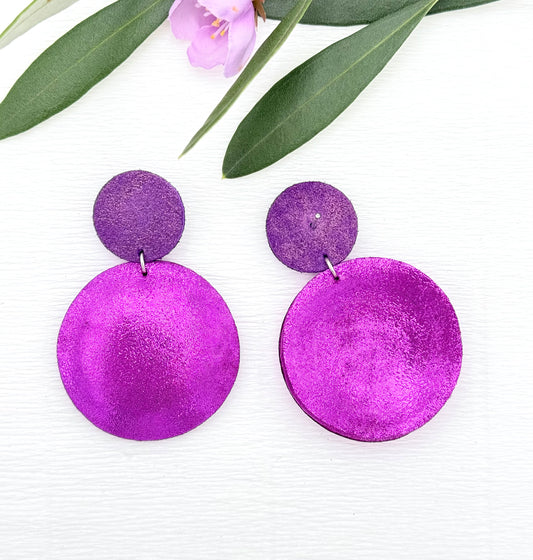 Schimmernde Ohrringe aus feinstem Leder mit einem runden Anhänger in einem dunklen Pinkton