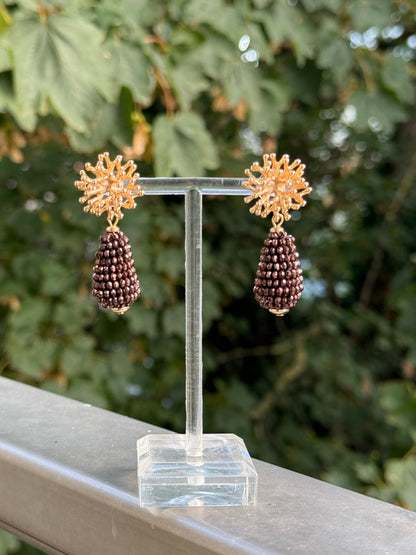 Goldene Korallstecker mit Glitzertropfen in glänzendem Braun