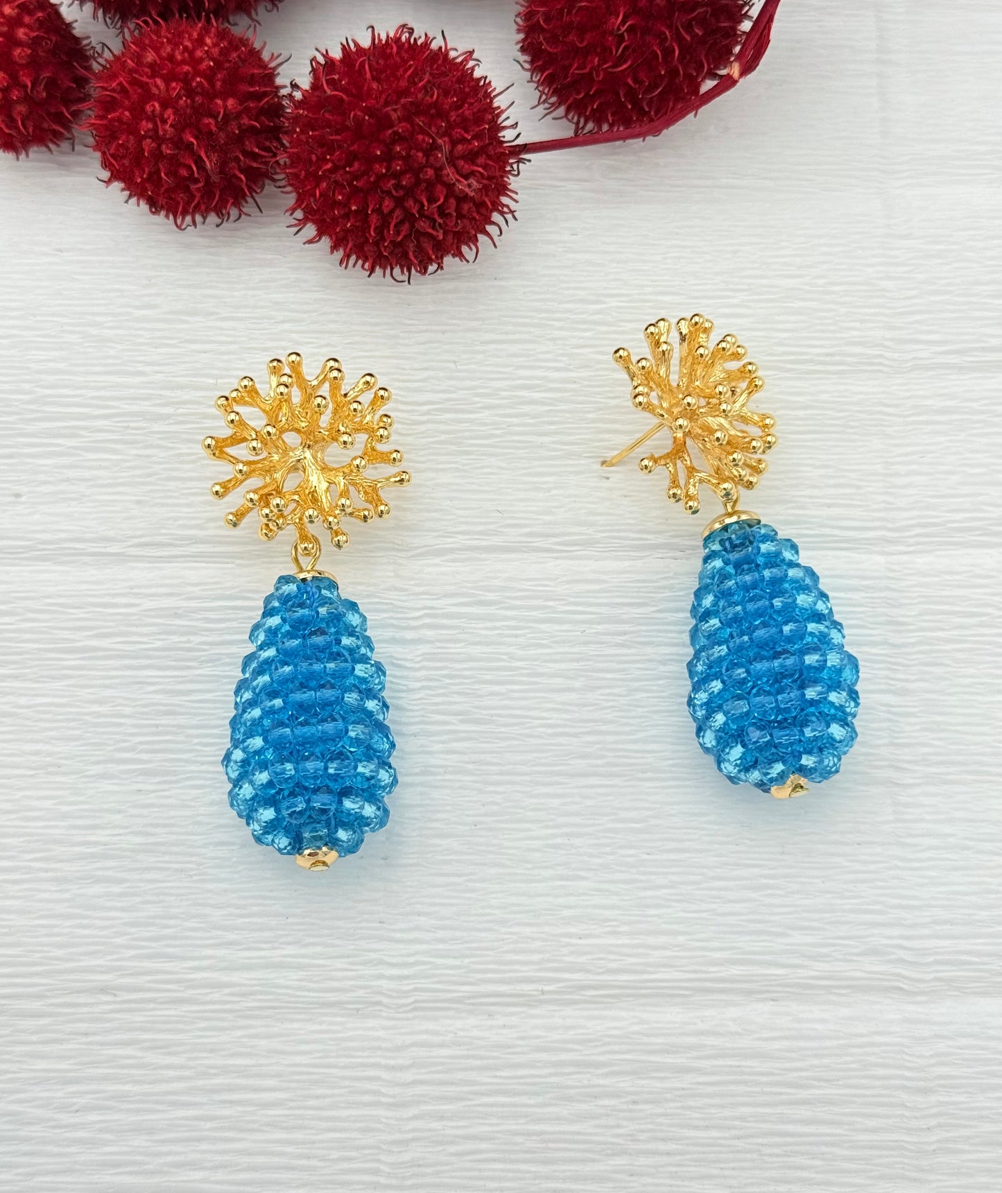 Schöne Ohrringe mit türkisem Glitzertropfen und Stecker in Korallenform